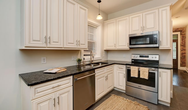 kitchen with dark hardwood / wood-style flooring, stainless steel appliances, sink, dark stone countertops, and hanging light fixtures