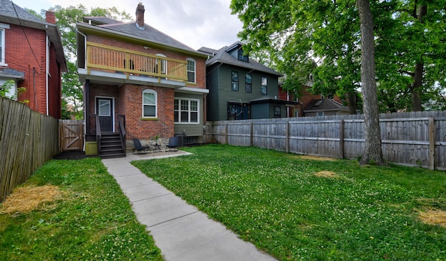 back of house with a yard and a balcony