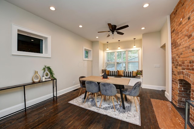 dining space featuring ceiling fan, dark hardwood / wood-style flooring, and brick wall