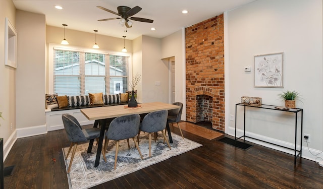 dining room with ceiling fan, a fireplace, and dark wood-type flooring