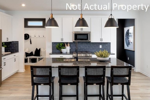 kitchen with hanging light fixtures, dark stone counters, and a center island with sink