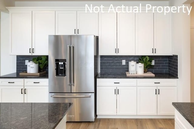 kitchen with white cabinetry, tasteful backsplash, high quality fridge, and light hardwood / wood-style floors