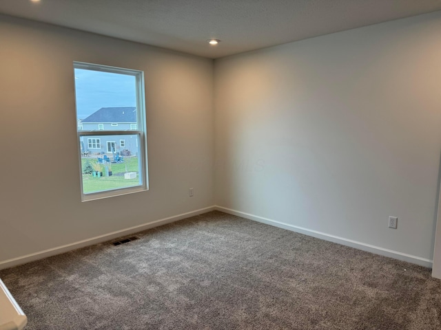 empty room with dark carpet and a wealth of natural light