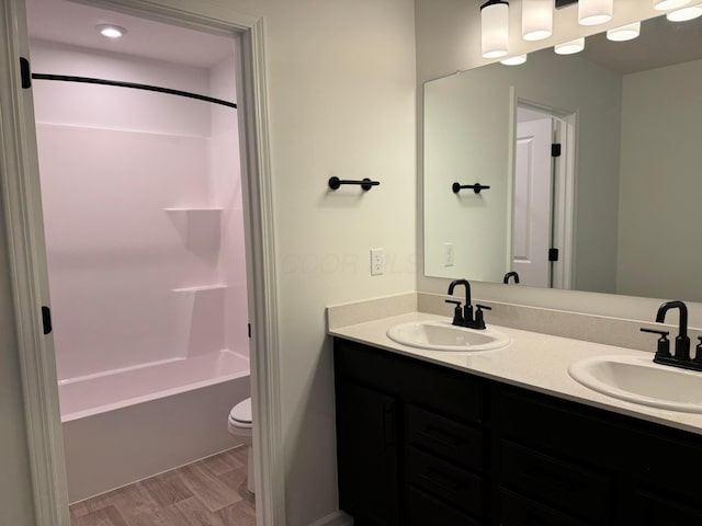 full bathroom with vanity, wood-type flooring,  shower combination, and toilet