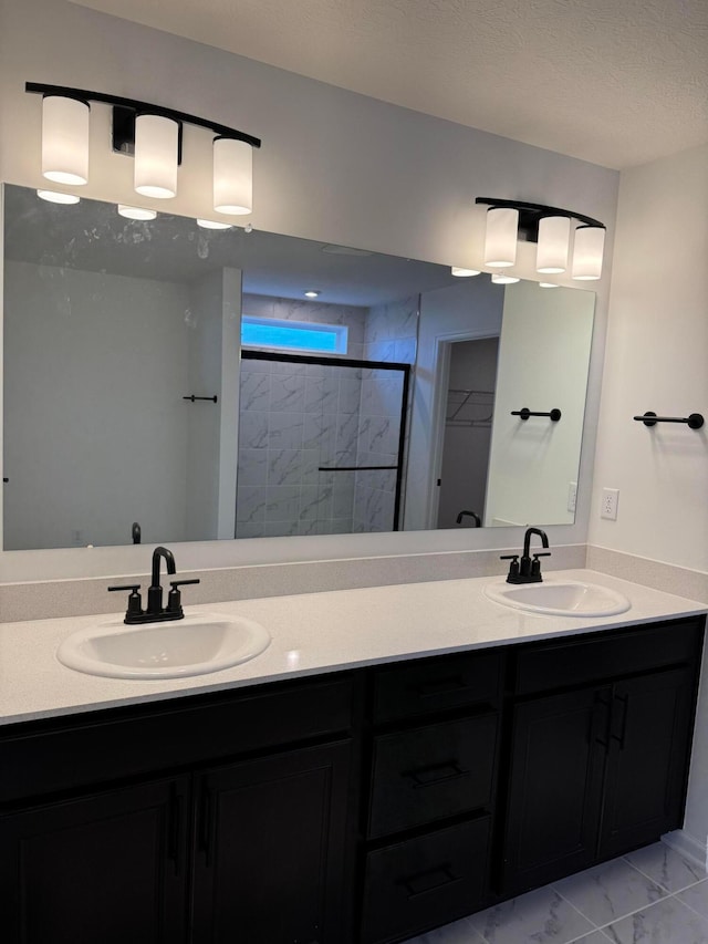 bathroom with vanity, a textured ceiling, and tiled shower