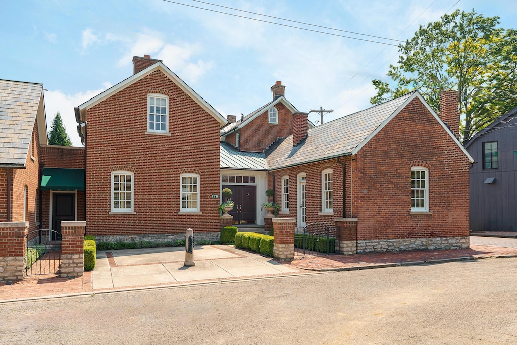 view of front of property with a fenced front yard, brick siding, a chimney, and a standing seam roof