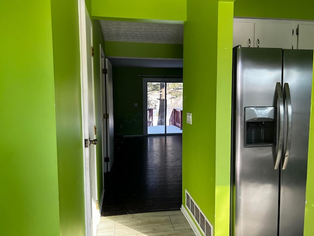 corridor with a textured ceiling and light tile patterned flooring