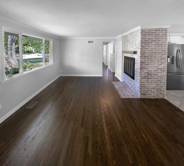 unfurnished living room featuring ornamental molding, dark wood-type flooring, and a brick fireplace