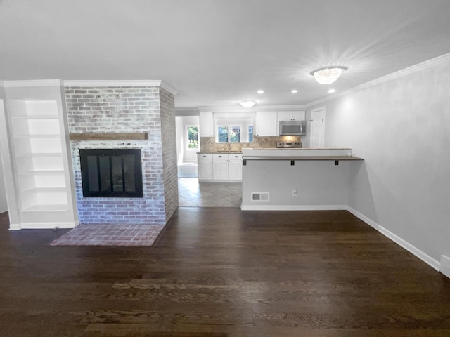 interior space featuring sink, a fireplace, crown molding, and dark wood-type flooring