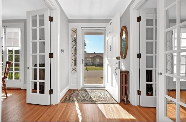 entrance foyer featuring light hardwood / wood-style floors, ornamental molding, and french doors