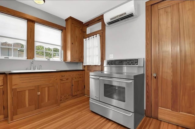 kitchen with an AC wall unit, electric stove, sink, and light wood-type flooring