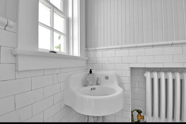 bathroom featuring sink, tile walls, and radiator