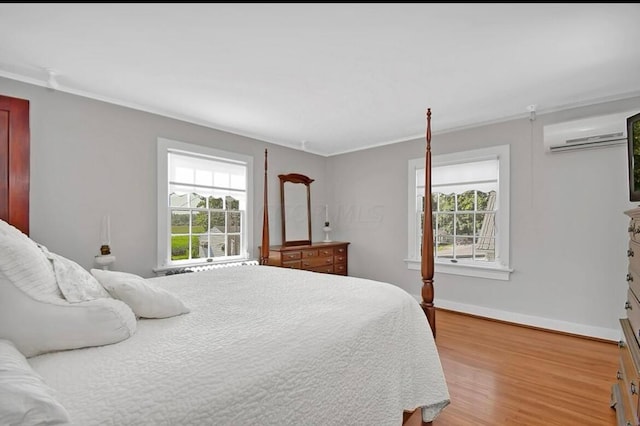 bedroom with a wall mounted air conditioner, hardwood / wood-style floors, and crown molding