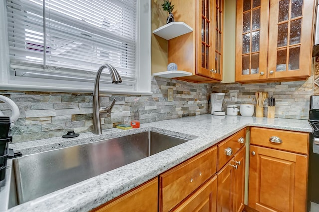 kitchen with light stone counters, range with electric stovetop, sink, and backsplash