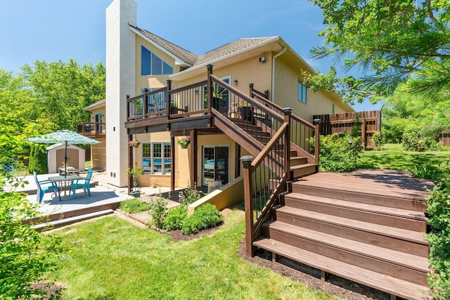 back of property with a wooden deck, a storage unit, a yard, and a patio area