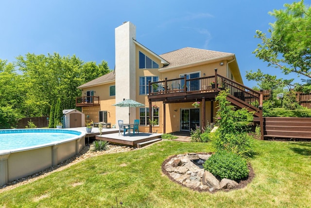 back of property featuring a pool side deck, a lawn, and a shed