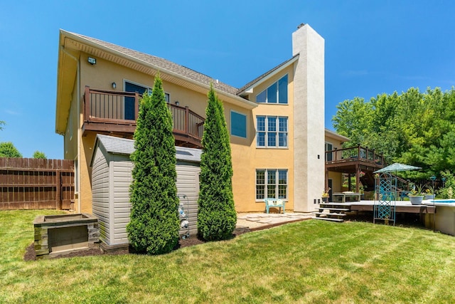 back of house with a wooden deck, a patio area, and a lawn