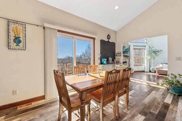 dining room with hardwood / wood-style flooring and high vaulted ceiling