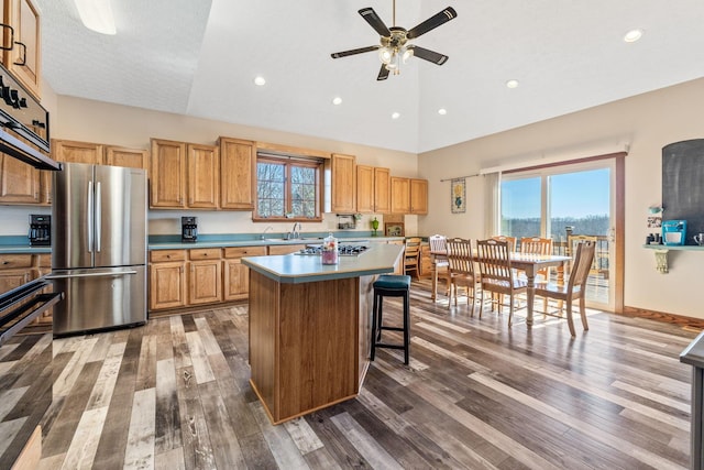 kitchen featuring wood-type flooring, stainless steel fridge, sink, and a kitchen island