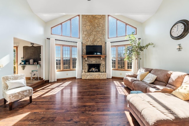 living room with dark hardwood / wood-style flooring, a stone fireplace, and high vaulted ceiling