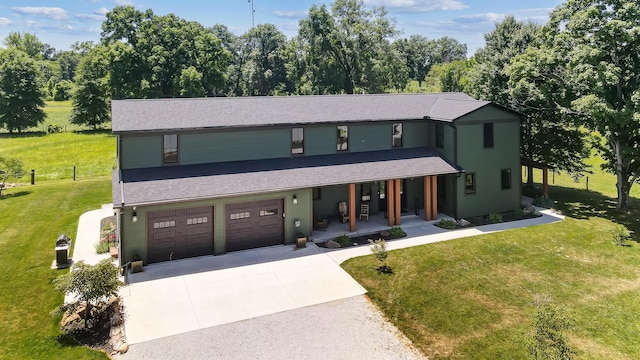 view of front of property featuring covered porch, a garage, and a front yard