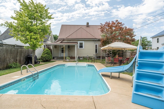 view of swimming pool featuring a patio area, area for grilling, and a water slide