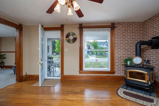 interior space featuring ceiling fan, a healthy amount of sunlight, light wood-type flooring, and a wood stove