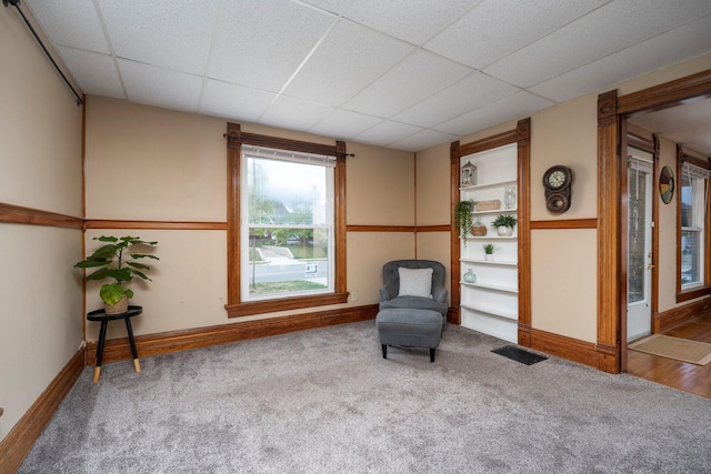 unfurnished room featuring carpet flooring, a paneled ceiling, and built in features