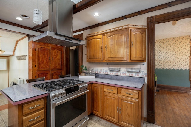 kitchen with island exhaust hood, kitchen peninsula, light hardwood / wood-style floors, decorative light fixtures, and stainless steel stove