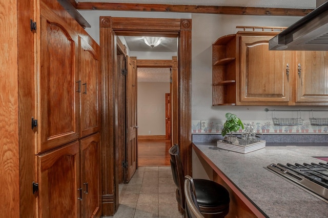 kitchen with stainless steel cooktop, light tile patterned floors, and range hood