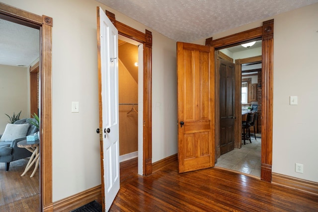 hallway with a textured ceiling and dark wood-type flooring