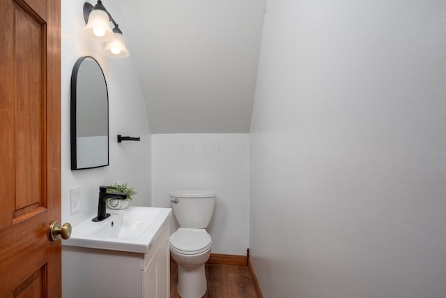 bathroom featuring toilet, wood-type flooring, sink, and vaulted ceiling