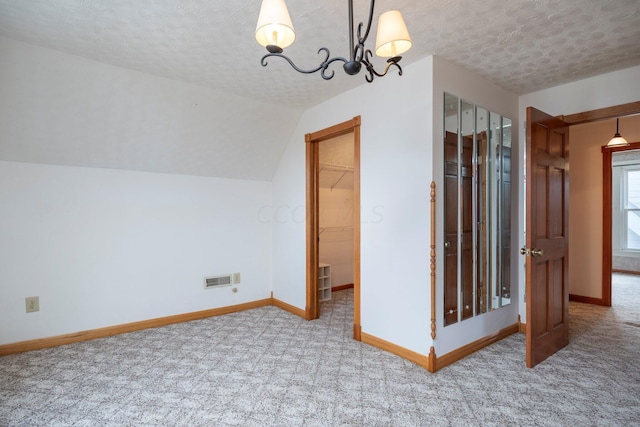 additional living space with a textured ceiling, carpet floors, an inviting chandelier, and vaulted ceiling