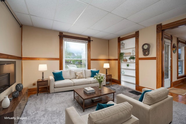 living room with a paneled ceiling and light hardwood / wood-style floors