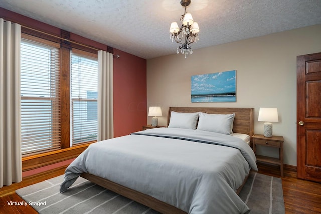 bedroom featuring a chandelier, wood-type flooring, and a textured ceiling