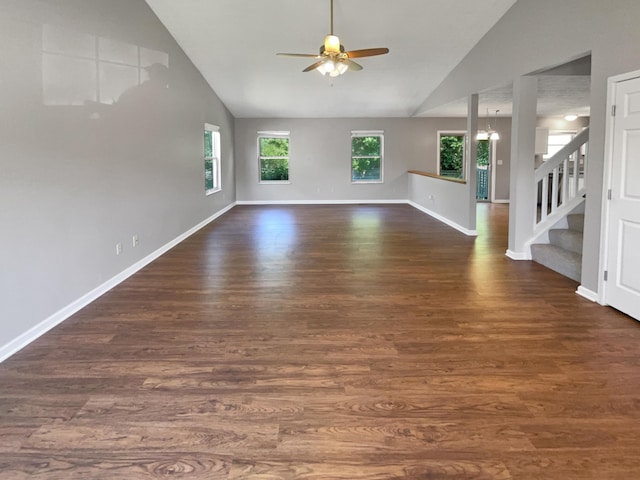 unfurnished living room with ceiling fan with notable chandelier, dark hardwood / wood-style flooring, a wealth of natural light, and lofted ceiling