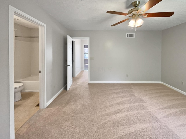 spare room featuring light carpet, ceiling fan, and a textured ceiling