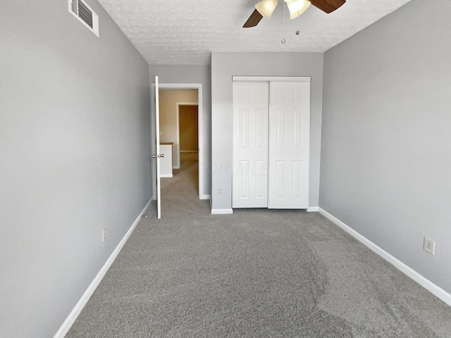 unfurnished bedroom with ceiling fan, carpet floors, a textured ceiling, and a closet