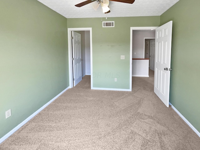 unfurnished bedroom with ceiling fan, a textured ceiling, and light carpet