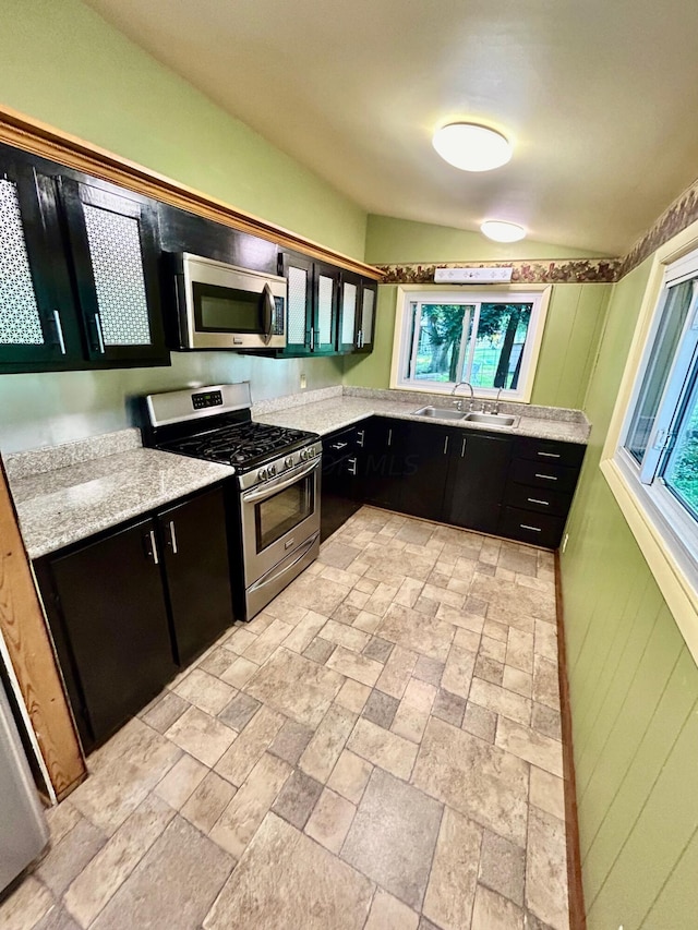 kitchen with a wealth of natural light, sink, stainless steel appliances, and light stone counters