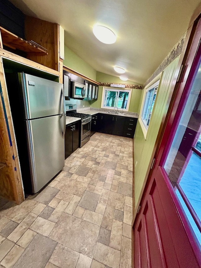 kitchen with sink, appliances with stainless steel finishes, and vaulted ceiling