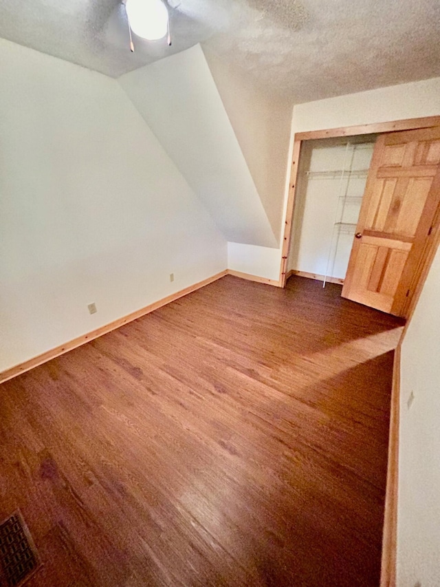 additional living space featuring a textured ceiling, dark hardwood / wood-style floors, and lofted ceiling