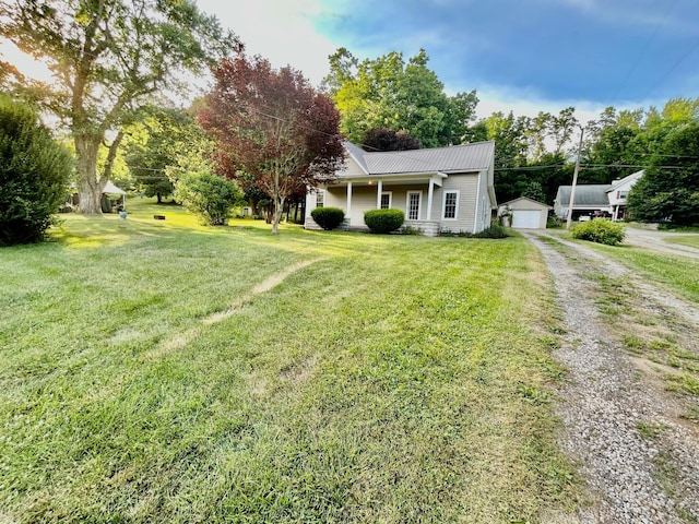 view of front facade featuring an outbuilding, a garage, a front lawn, and covered porch