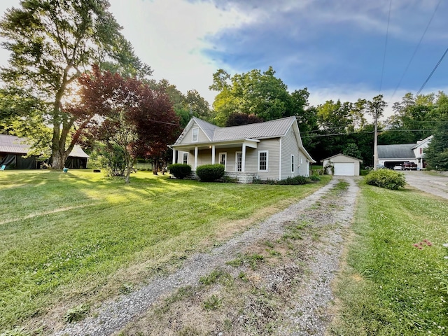 view of front facade featuring a porch, a garage, an outbuilding, and a front yard