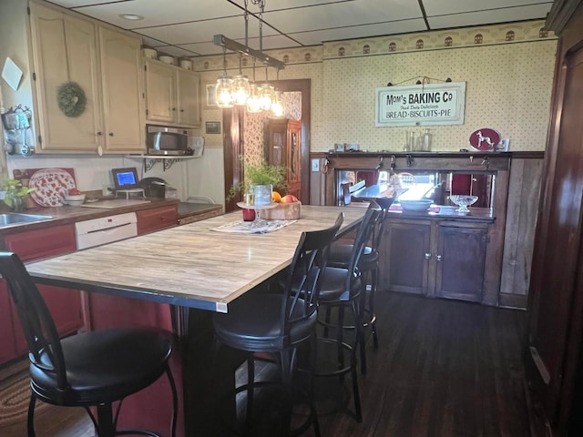 kitchen featuring pendant lighting, dark hardwood / wood-style floors, white dishwasher, and sink