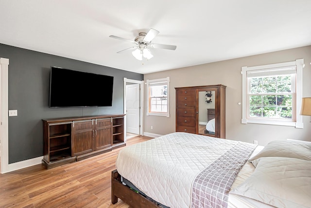 bedroom featuring ceiling fan, wood-type flooring, and multiple windows