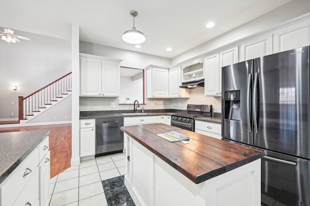 kitchen with appliances with stainless steel finishes, a kitchen island, sink, butcher block countertops, and white cabinetry