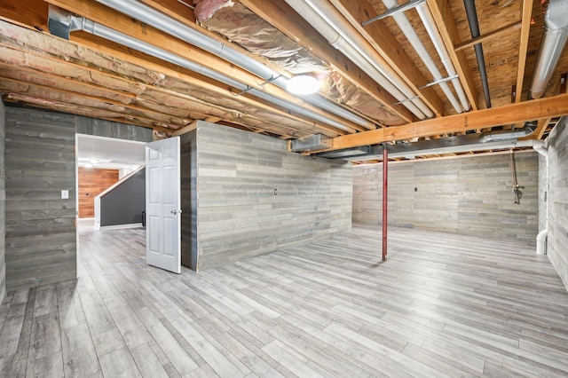 basement featuring wood walls and light hardwood / wood-style floors