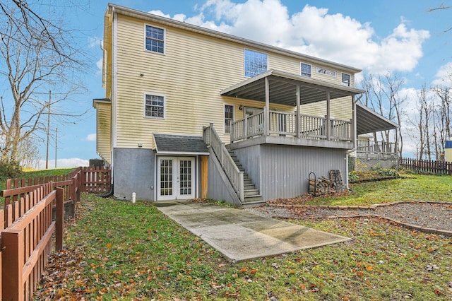 rear view of property with french doors, a deck, and a lawn