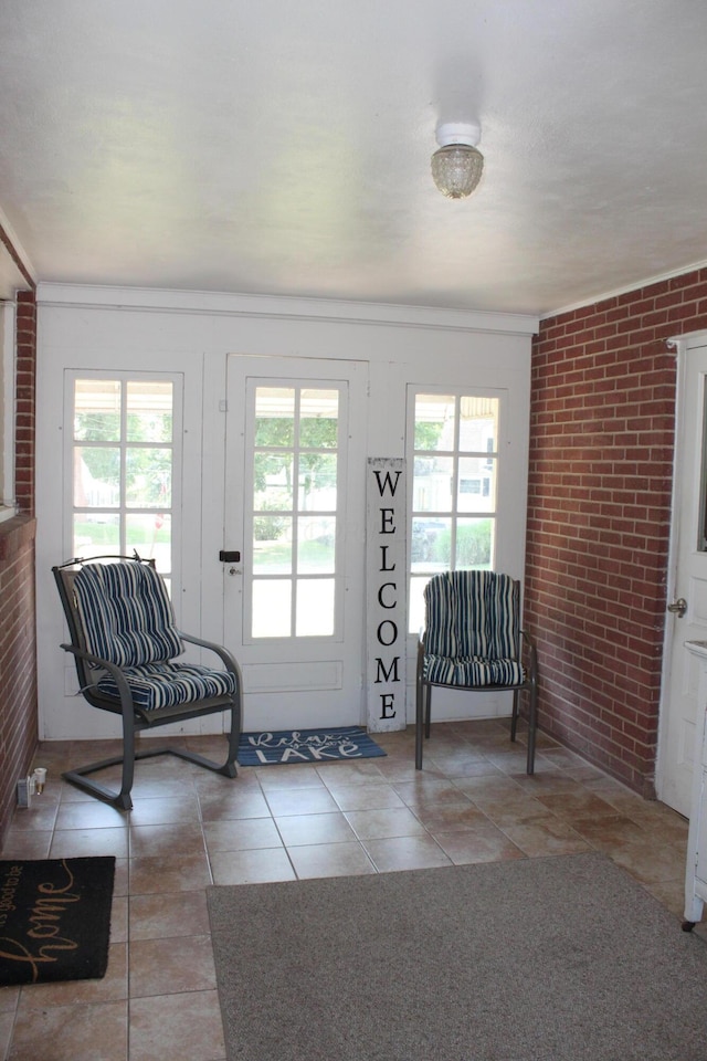 entrance foyer with light tile patterned floors, brick wall, and ornamental molding